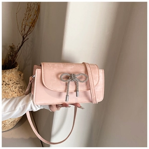 Close-up of pink leather crossbody bag featuring a sparkling rhinestone bow buckle detail