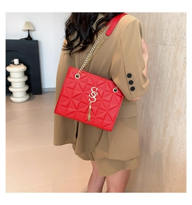 Detail of red geometric quilted bag with gold S logo and tassel on shoulder