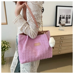Pink quilted tote bag detail with leather strap, metal chain, and plush pom-pom charm