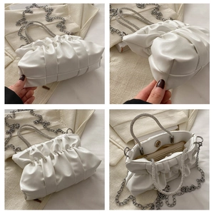 Detail van witte geplooide emmertas met strass handvat en zilveren ketting schouderriem
