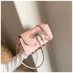 Detailed view of a pink textured leather handbag with a silver rhinestone bow detail