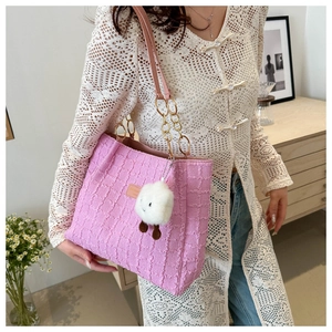 Detail of pink pleated tote bag with chain strap and cute plush charm on a casual outfit