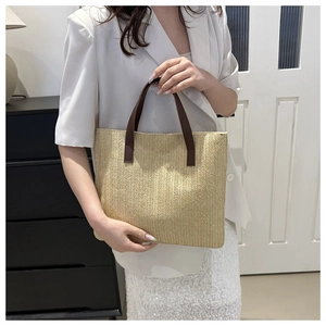 Close-up of beige herringbone weave texture and brown leather handle on tote bag