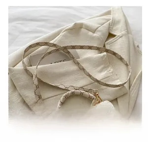 Dettaglio della tracolla regolabile e trama monogram vintage sulla borsa color crema