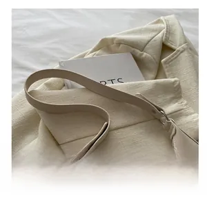 Detail of cream white faux leather shoulder bag with smooth texture and metal hardware