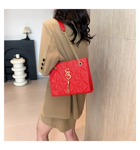 Detail of red quilted leather bag with gold chain strap and metal logo decoration
