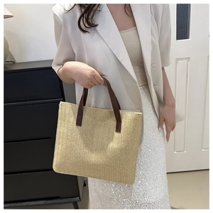 Detail of V-shaped woven texture on beige straw tote bag with brown leather handles