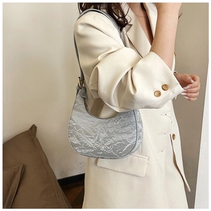 Detailed view of silver pleated crescent hobo bag with metallic texture and gold zipper