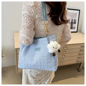 Detail of light blue pleated tote with checkerboard texture and plush cloud charm