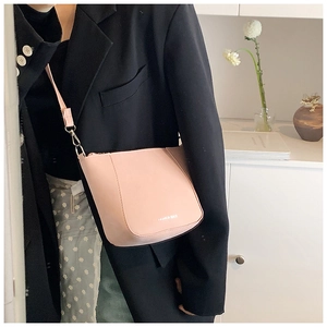 Dettaglio di una borsa a secchiello rosa pallido con scritta Fashion Bags e ganci in metallo