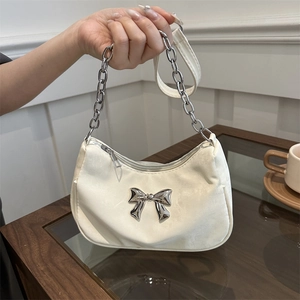 Chic off-white underarm bag with silver bow accent and chain strap in indoor setting