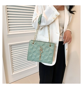 Close-up of mint green geometric shoulder bag with gold hardware and tassel detail