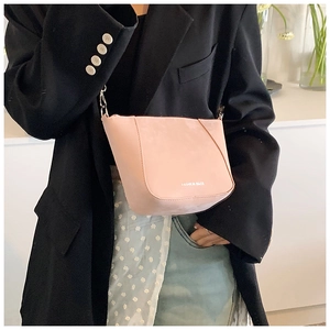 Borsa a secchiello rosa opaca con dettagli argento indossata su un blazer nero