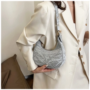 Detailed close-up of a silver crescent moon bag with crinkled texture on a model