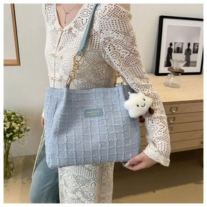 Close-up of light blue checkered tote bag with gold chain strap and plush cloud charm