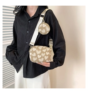 Detail of canvas heart crossbody bag with matching round pouch and wide strap