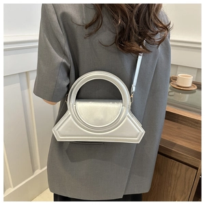 Dettaglio della borsa geometrica argento con grande manico circolare e tracolla sottile