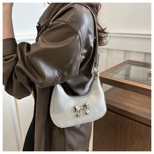 Detail shot of light gray moon-shaped hobo bag with a silver metallic bow accent