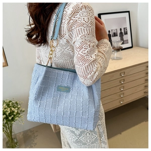 Detail of light blue tweed tote bag with textured weave and gold chain strap detail