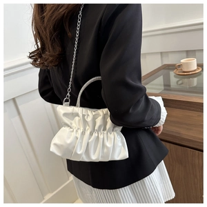Detail van witte geplooide handtas met strass handvat en zilveren kettingriem