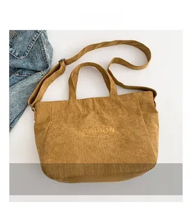 Macro detail of the brown corduroy tote bag showing the fashion embroidery and adjustable strap