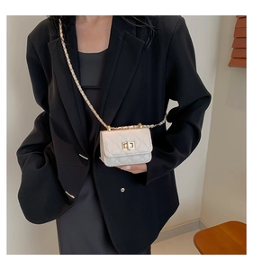 Close-up of cream quilted crossbody bag with gold chain strap and metal turn-lock closure