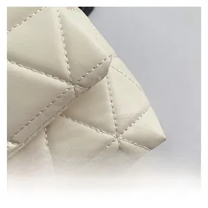 Close-up of beige quilted leather texture and precision stitching on the shoulder bag
