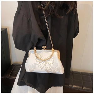 Detailed shot of white silk evening clutch with vintage gold clasp and pearl embroidery
