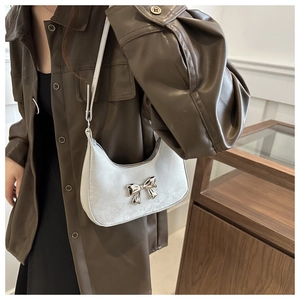 Close-up of silver crescent hobo bag featuring a 3D metallic bow decoration
