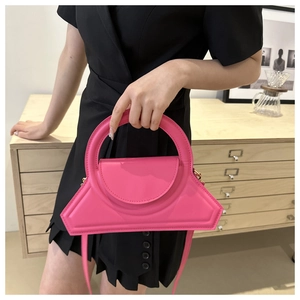 Dettaglio della borsa rosa geometrica con grande manico rotondo e finitura in pelle liscia