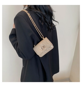 Detailed view of beige quilted mini bag with gold chain strap on black blazer