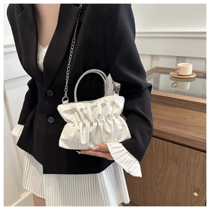 Macro view of white pleated evening bag with sparkling crystal handle and silver chain