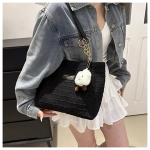 Detail view of black tote bag with textured geometric pattern and white lamb plush charm