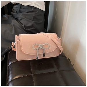 Pink crossbody bag featuring a sparkling crystal bow and textured suede finish