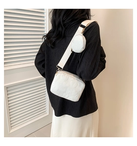 Detailed back view of white heart embossed crossbody bag set with small round pouch charm