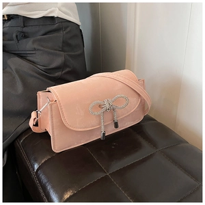 Detailed view of pink suede crossbody bag featuring a sparkling crystal bow and metal tassels