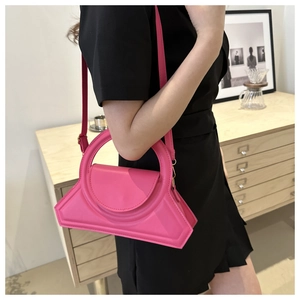 Borsa geometrica rosa acceso con manico rotondo abbinata a un abito nero chic