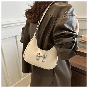 Detail of cream white leather hobo bag with silver metallic bow and slim shoulder strap