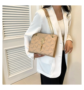 Detail of beige quilted chain shoulder bag with gold metal letter pendant for women