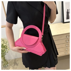 Dettaglio della borsa geometrica rosa acceso abbinata a un elegante blazer nero