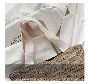 Détail du sac cabas en paille tressée avec poignées en toile crème et bouton pression