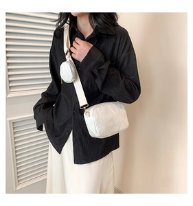 Close-up of white heart-embossed crossbody bag with matching round coin purse detail