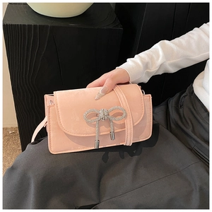 Detail of pink suede crossbody bag with rhinestone bow and metal tassels decoration
