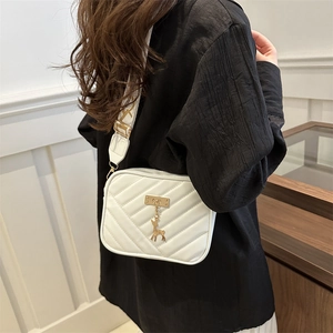 White quilted crossbody bag with golden deer pendant and wide patterned strap for women