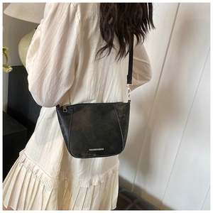 Dettaglio di una borsa a tracolla vintage in pelle nera con testo bianco e cinturino