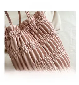 Close-up of pink drawstring bucket bag featuring elegant pleated texture and premium stitching