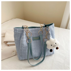 Detail of light blue tweed tote bag with gold chain strap and plush cloud charm