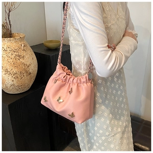Detailansicht der rosa Leder-Beuteltasche mit Schmetterlings-Metallelementen und Kette