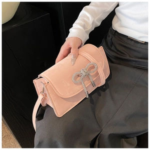 Detail view of a pink crossbody bag featuring a sparkling silver rhinestone bow decoration