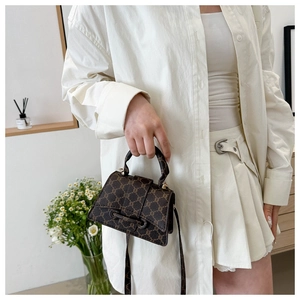 Dettaglio borsa a mano marrone con monogramma, hardware dorato e manico superiore